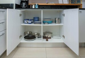 Una cocina con armarios blancos, cafetera y diverso menaje.