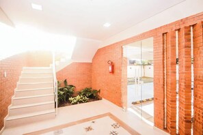 Eine Treppe führt zu einer zweiten Etage, ein Feuerlöscher ist an der Wand befestigt und ein Glastür-Eingang ist vorhanden.