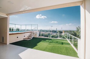 Ein modernes Interieur mit einem Balkon, künstlichem Rasen und Blick auf eine Baustelle.