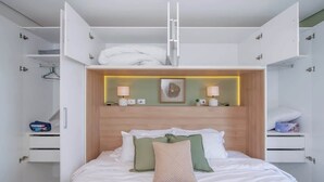 A bedroom with a bed, bedside tables, a wardrobe, and a headboard with integrated lighting. - Stunning 1BR Apt with amazing City Views (Asunción)