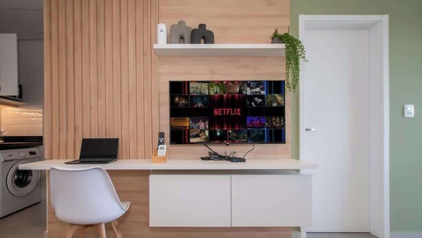 A modern kitchen with a built-in Netflix display, a laptop, and a white chair. - Stunning 1BR Apt with amazing City Views (Asunción)