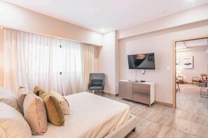 A hotel room with a bed, a TV, a desk, and a chair. - Regatta Living Prime Location, Stunning Amenities (Santo Domingo)