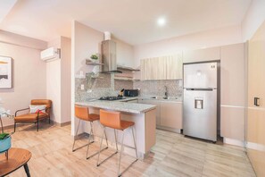 A modern kitchen with a central island, bar stools, a stainless steel refrigerator, and a built-in oven. - Regatta Living Prime Location, Stunning Amenities (Santo Domingo)