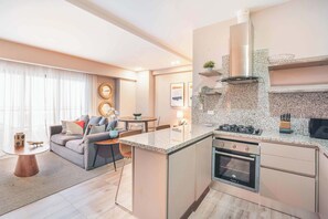 A modern kitchen with a built-in oven, granite countertop, and a dining area with a sofa and table. - Regatta Living Prime Location, Stunning Amenities (Santo Domingo)