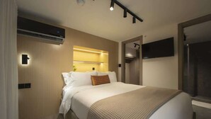 Ein modernes Hotelzimmer mit einem großen Bett, einem Flachbildfernseher und einer eingebauten Klimaanlage.