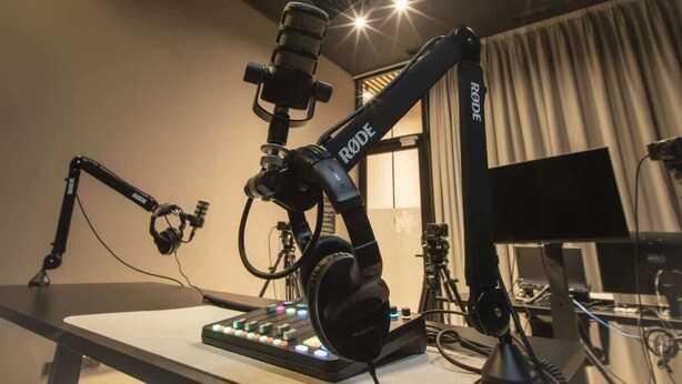 Eine professionelle Audioanlage mit Mikrofon, Kopfhörern und Mischpult in einem Raum mit Vorhängen und Fenster.