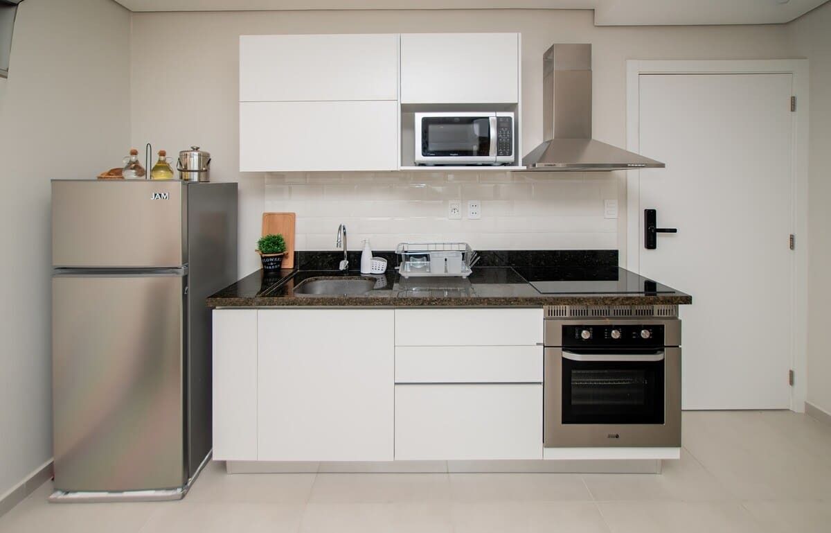 Une cuisine moderne avec des meubles blancs, un réfrigérateur en acier inoxydable, un four à micro-ondes, une cuisinière et un lave-vaisselle.