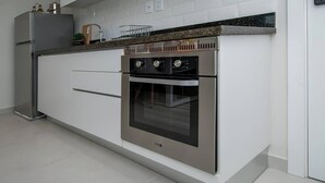 Een moderne keuken met een ingebouwde oven, een koelkast van roestvrij staal en een granieten aanrecht.
