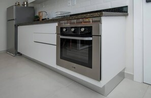 A modern kitchen with a built-in oven, a stainless steel refrigerator, and a granite countertop. - Modern 1BR with Desk & Panoramic View (Asunción)