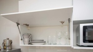 Een keuken met witte kastjes, een magnetron en een waterkoker.