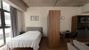 Ein modernes Hotelzimmer mit Bett, einer Holzwand, einem Essbereich und einer Küchenzeile.