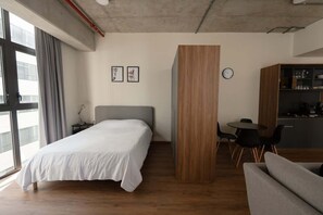 Ein modernes Hotelzimmer mit Bett, einer Holzwand, einem Essbereich und einer Küchenzeile.