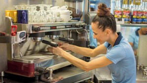Eine Person bedient eine Espressomaschine in einer gewerblichen Umgebung.