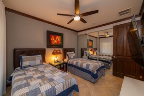 Une chambre d’hôtel avec deux lits, un ventilateur de plafond, un miroir et une table de chevet avec des lampes.