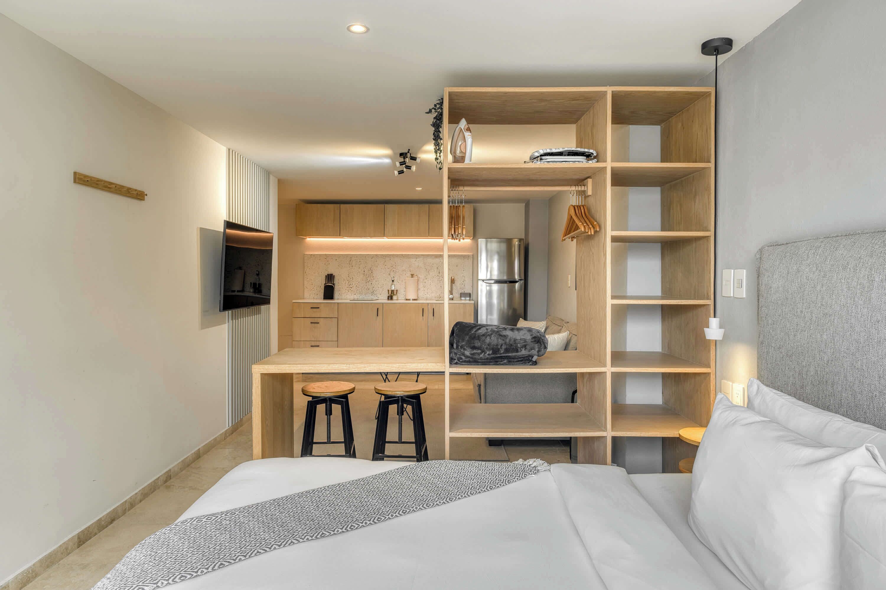 A compact room with a bed, a kitchenette, and a small seating area.