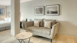 A modern living room with a beige sofa, a round coffee table, and two framed pictures on the wall. - Modern King Studio in Central Roma Norte (Ciudad de México)