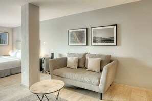A modern living room with a beige sofa, a round coffee table, and two framed pictures on the wall. - Modern King Studio in Central Roma Norte (Ciudad de México)