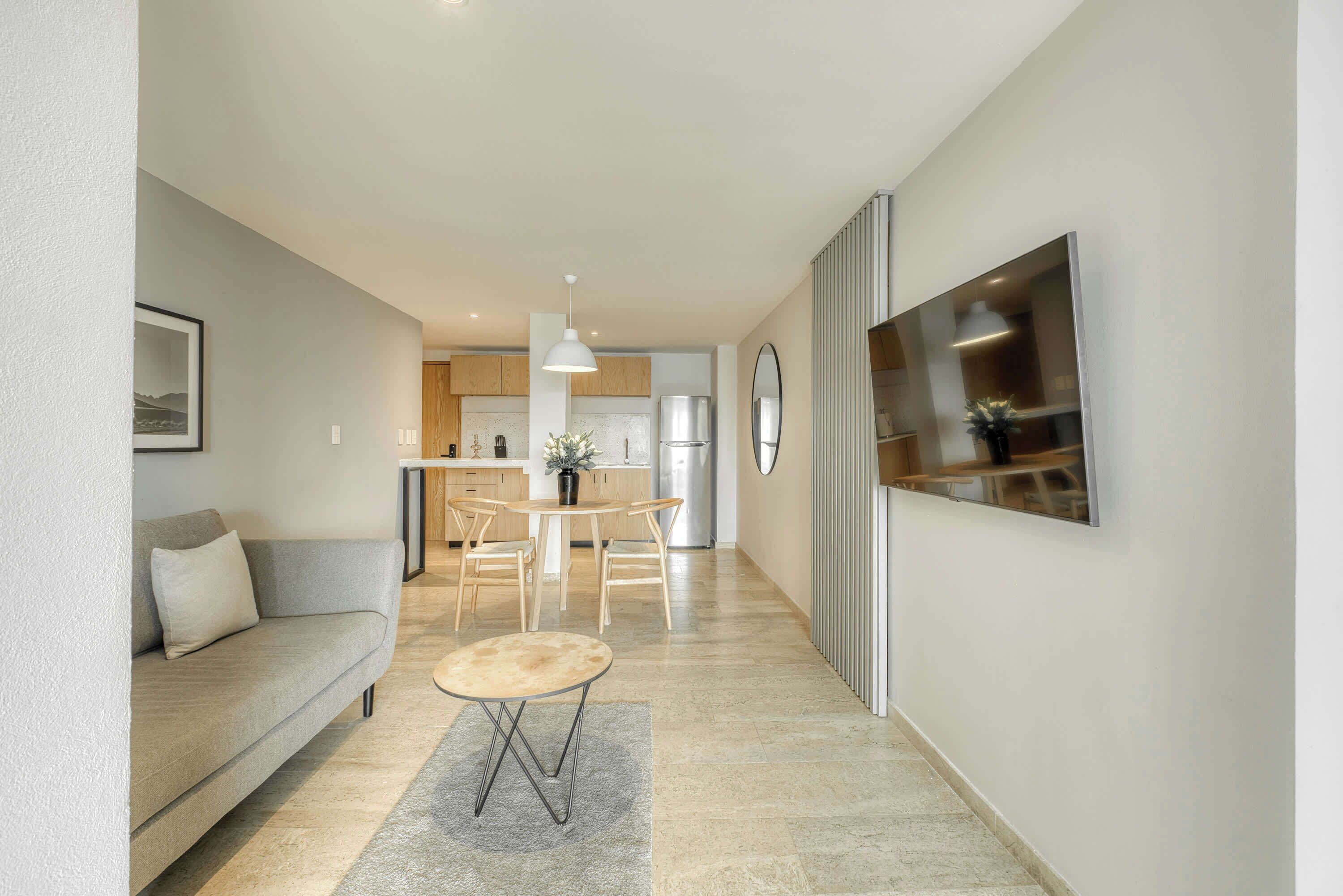 A modern living room with a sofa, a small round table, and a TV mounted on the wall.