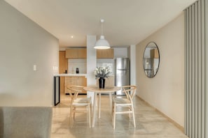 Eine moderne Küche mit Holzschränken, einem Edelstahlkühlschrank und einem Essbereich mit Tisch und Stühlen.
