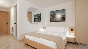 Quarto moderno com cama, mesa de cabeceira, espelho e duas imagens emolduradas na parede.