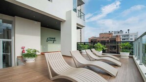 Een terras op het dak met lounge fauteuils, potplanten en een bordje met de tekst 'TERRE lounge'.