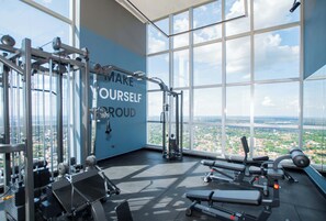 A gym with a large window, a motivational quote on the wall, and various exercise equipment. - Urban 1-Bedroom Escape in Petra Tower Asuncion (Asunción)