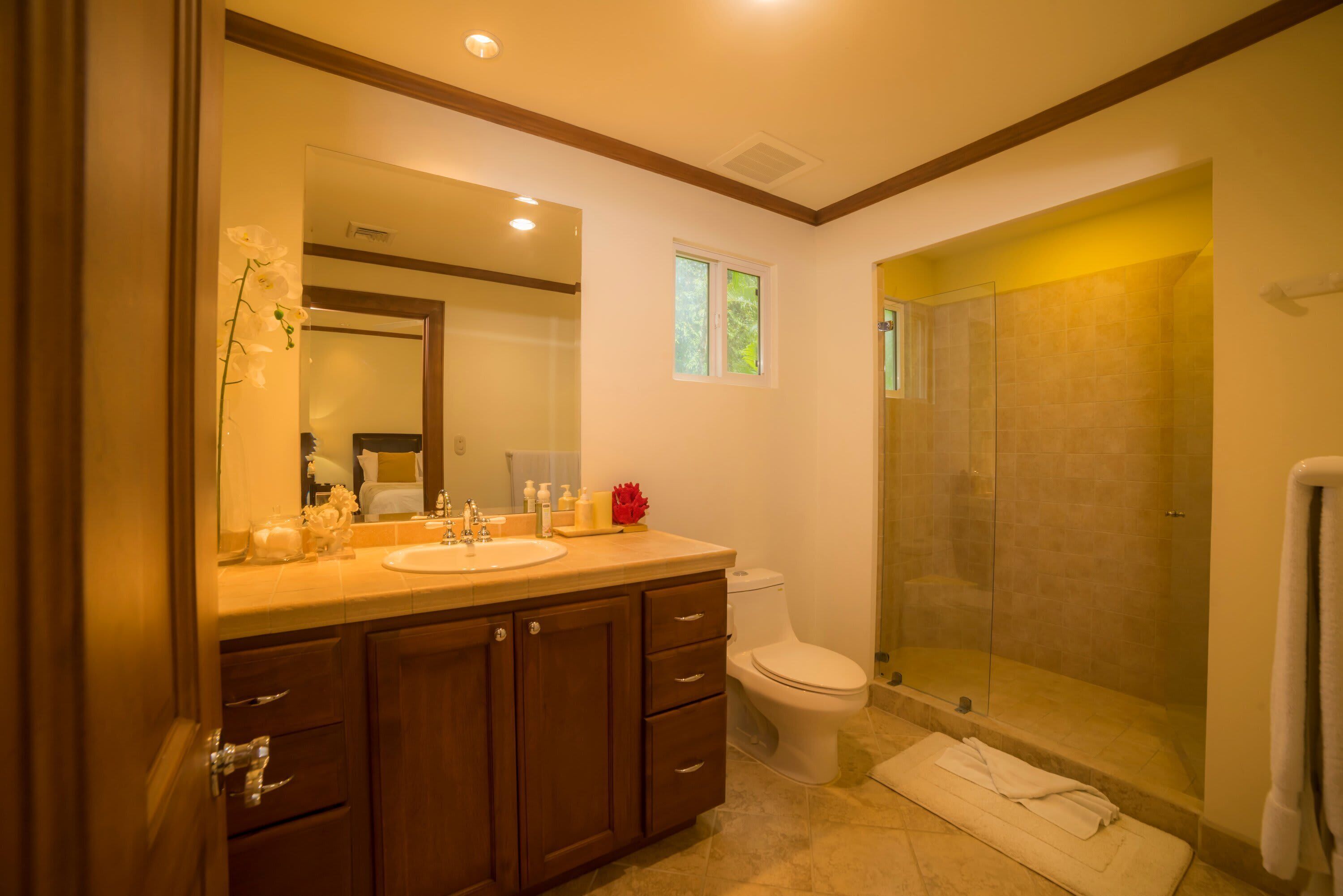A bathroom with a double sink vanity, a toilet, and a glass-enclosed shower.