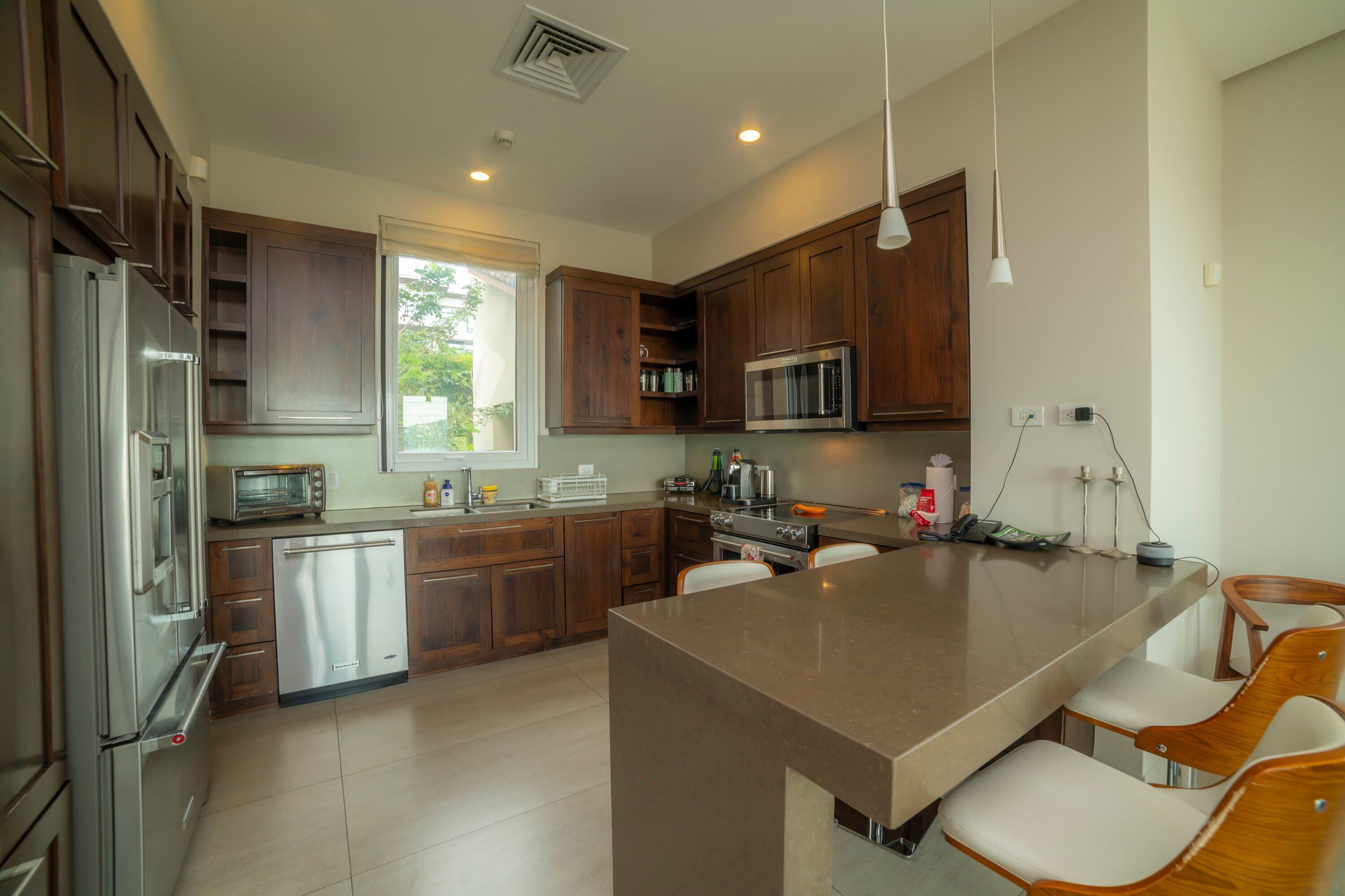Una cocina moderna con electrodomésticos de acero inoxidable, armarios de madera y una isla grande con taburetes de bar.