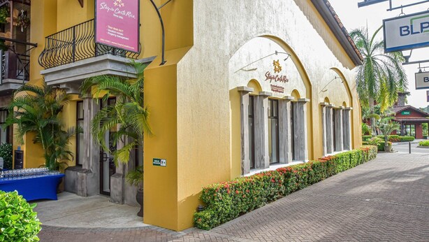 Um hotel com fachada amarela, varanda com grade de ferro e placa indicando os serviços.