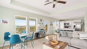 A modern living room with a dining area, kitchen, and a ceiling fan. - Hot Tub, Pet Friendly, 4Bdr 2Bth, - Aqua Vista (Bolivar Peninsula)