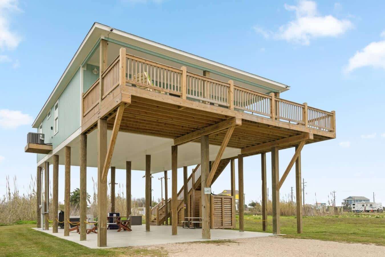 A two-story wooden structure with a balcony, a covered lower level, and a staircase.