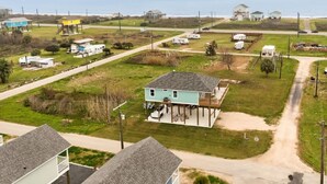 A coastal property with a large house featuring a deck, a fenced yard, and a view of the ocean. - Hot Tub, Pet Friendly, 4Bdr 2Bth, - Aqua Vista (Bolivar Peninsula)