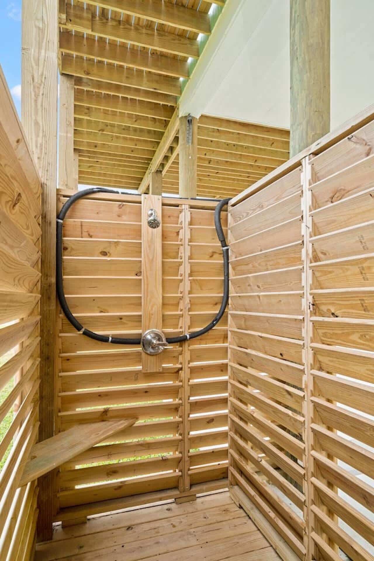 A wooden sauna with a curved door and a black hose.