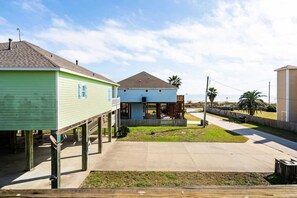 A coastal property with a green house, a blue house, and a beige building, connected by a concrete pathway. - Gulf Views, Pet Friendly, Deck (Bolivar Peninsula)