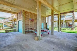 A covered outdoor area with a picnic table, chairs, and a staircase leading to an upper level. - Gulf Views, Pet Friendly, Deck (Bolivar Peninsula)