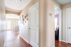A hallway with white doors, a dining area with chairs, and a ceiling light fixture. - Gulf Views, Pet Friendly, Deck (Bolivar Peninsula)