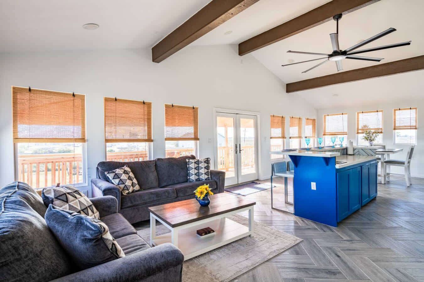 A spacious living area with a sofa, coffee table, and a blue kitchen island.