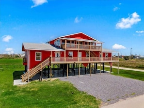 A red two-story house with a balcony and a staircase leading to the entrance. - Unit C of Crystal Beach's Premier Triplex 2Bd 1Bth (Bolivar Peninsula)