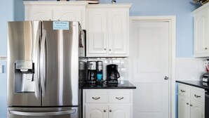 Una cocina con un refrigerador de acero inoxidable, una cafetera y un cartel de recogida de basura.