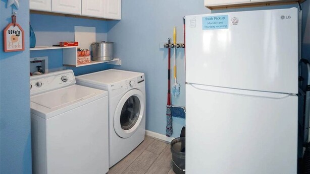 Un lavadero con lavadora, secadora y refrigerador, con un letrero de recogida de basura.