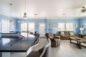 Amplia sala de estar con una isla grande, comedor y zona de estar con sofás y sillones.