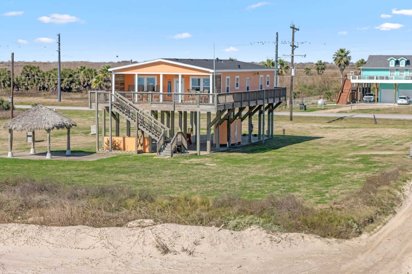 A two-story building with a balcony, a covered outdoor area, and a dirt road in the foreground.