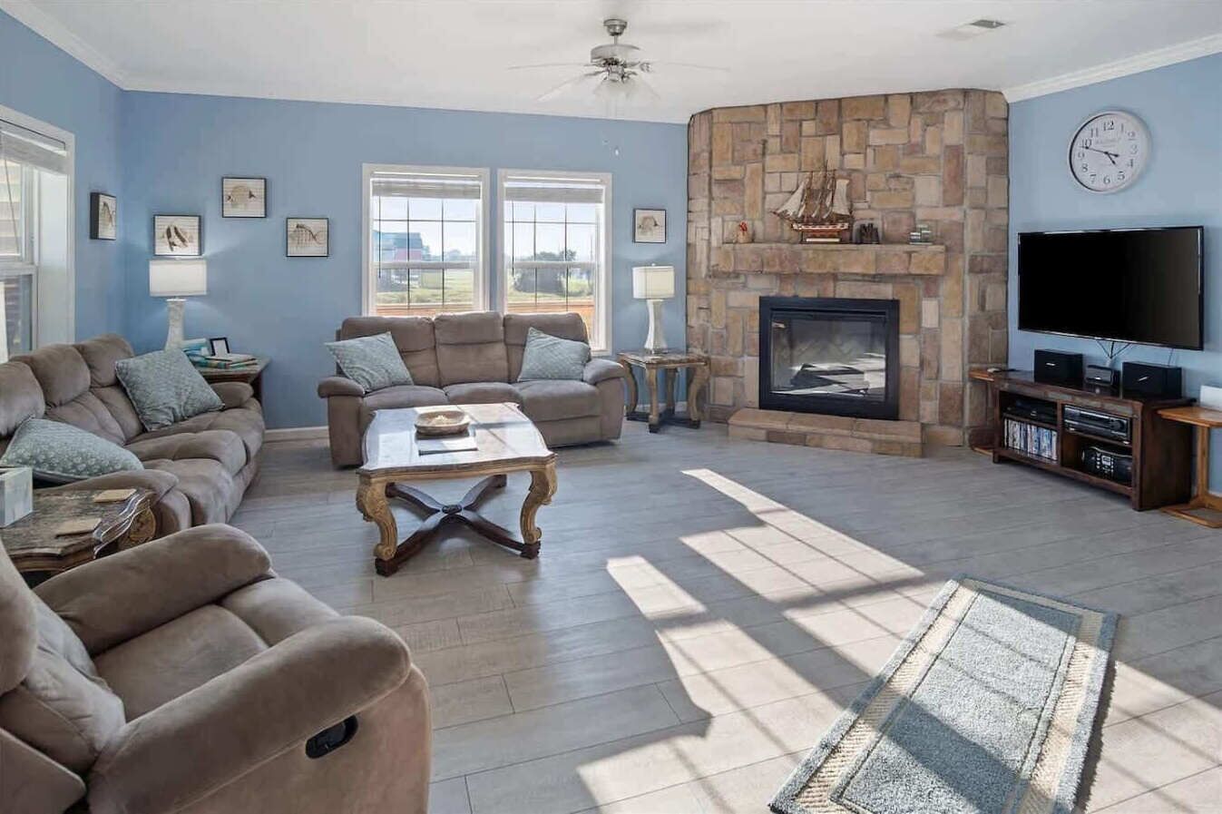 A living room with a stone fireplace, a flat-screen TV, and a large window.