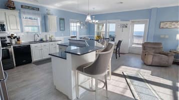 A modern kitchen with white cabinets, a central island, and a dining area with a chair.