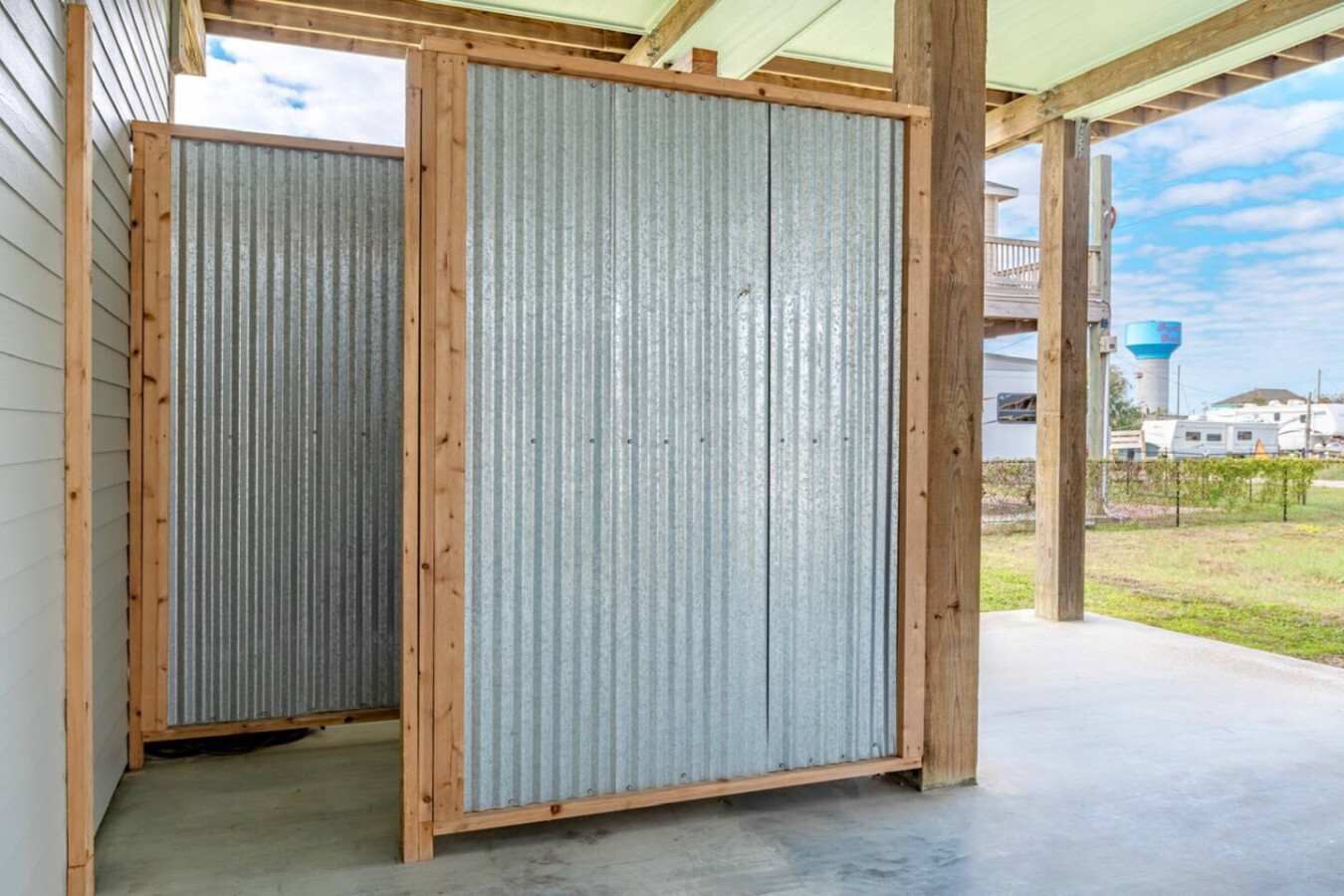 A covered outdoor area with a corrugated metal partition and wooden beams.