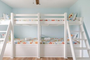 A bunk bed room with a light blue wall, wooden flooring, and floral bedding. - Fire Pit, Playscape, The Red Mermaid Retreat (Bolivar Peninsula)