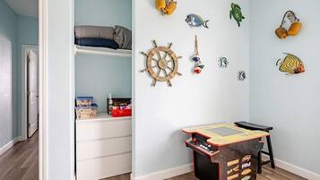 Una habitación infantil con cama, espacio de almacenamiento, una mesa de juegos y adornos en la pared.