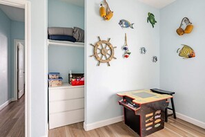 A child's room with a bed, storage, a play table, and wall decorations. - Fire Pit, Playscape, The Red Mermaid Retreat (Bolivar Peninsula)