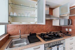 A modern kitchen with a stainless steel sink, a gas stove, and a microwave. - Capitalia  Business Center, Gym & Parking (Ciudad de México)