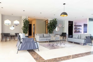 A modern living room with a sofa, chairs, a coffee table, and decorative plants. - Capitalia  Business Center, Gym & Parking (Ciudad de México)